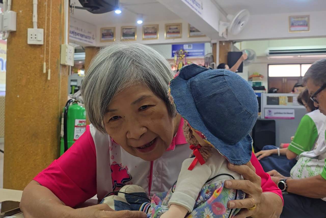 ผู้สูงอายุยิ้มและกอดเพื่อนคุย AI ระหว่างกิจกรรมที่ศูนย์ผู้สูงอายุ